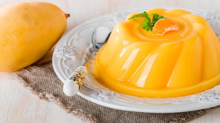 mango orange pudding on white plate with fruits on wooden table
