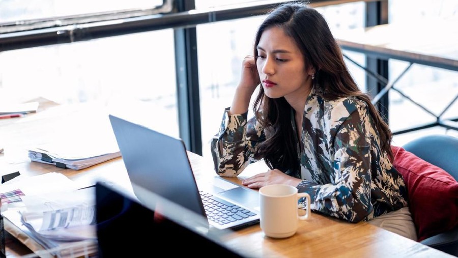 Sitting At A Desk And Working With Her Laptop Computer In The Office