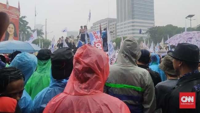 Massa buruh yang melakukan demo omnibus law di depan kompleks parlemen, Jakarta, terlihat terus melakukan aksi meski hujan deras.