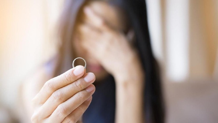 Ilustrasi perceraian The woman holds the wedding ring and weeps.