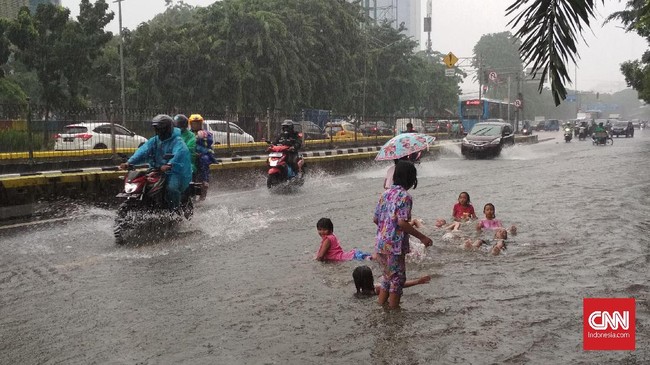 Sejumlah anak bermain di banjir yang menggenang di jalan Gunung Sahari setelah hujan yang mengguyur Jakarta dan sekitarnya sejak Jumat(24/1) pagi.