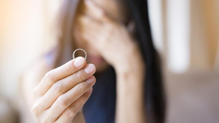 The woman holds the wedding ring and weeps.