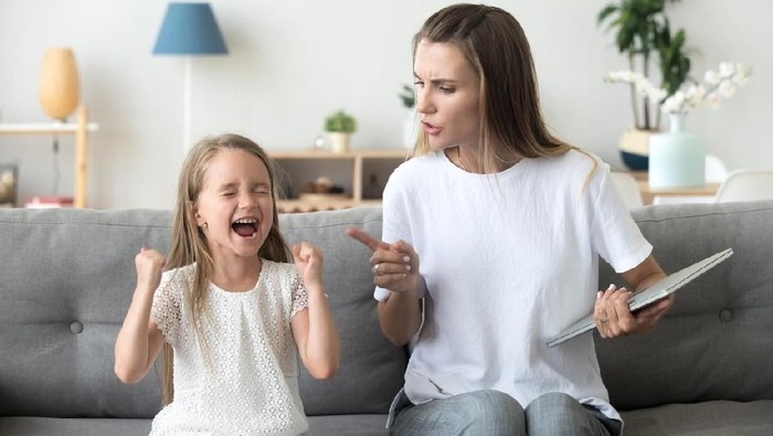Stressed exhausted mother looking at camera feeling desperate about screaming stubborn kid daughter tantrum, upset annoyed mom tired of naughty difficult child girl misbehave yelling for attention