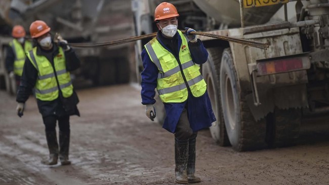 Workers carry materials at the construction site of a new hospital being built to treat patients from a deadly virus outbreak in Wuhan in China's central Hubei province on January 27, 2020. - China is rushing to build a new hospital in a staggering 10 days to treat patients at the epicentre of a deadly virus outbreak that has stricken thousands of people, state media reported on January 24. (Photo by Hector RETAMAL / AFP)