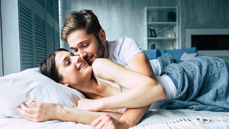 Couple in bed at home are kissing each other