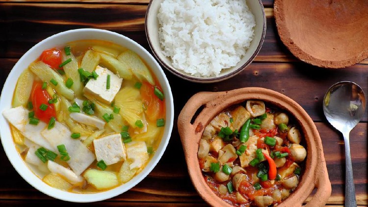 Top view vegetarian meal, vegetables soup from ingredient food as tomato, pineapple, bamboo shoot and tofu, mushroom cook with soy sauce, simple dish for vegan diet on wooden background