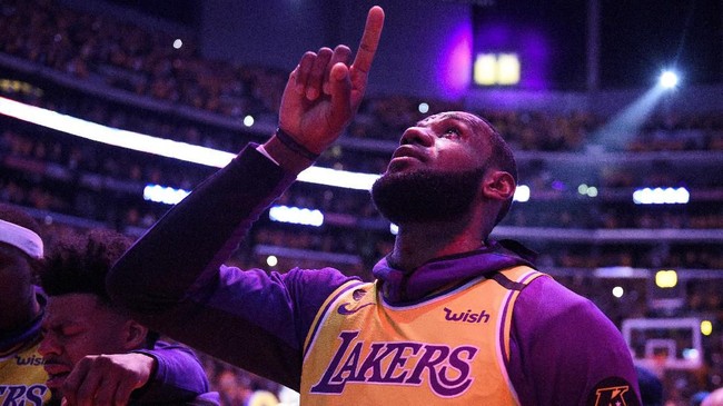 Los Angeles Lakers' LeBron James, wearing a No. 24 jersey, points up while shedding tears after the national anthem before the team's NBA basketball game against the Portland Trail Blazers in Los Angeles, Friday, Jan. 31, 2020. (AP Photo/Kelvin Kuo)