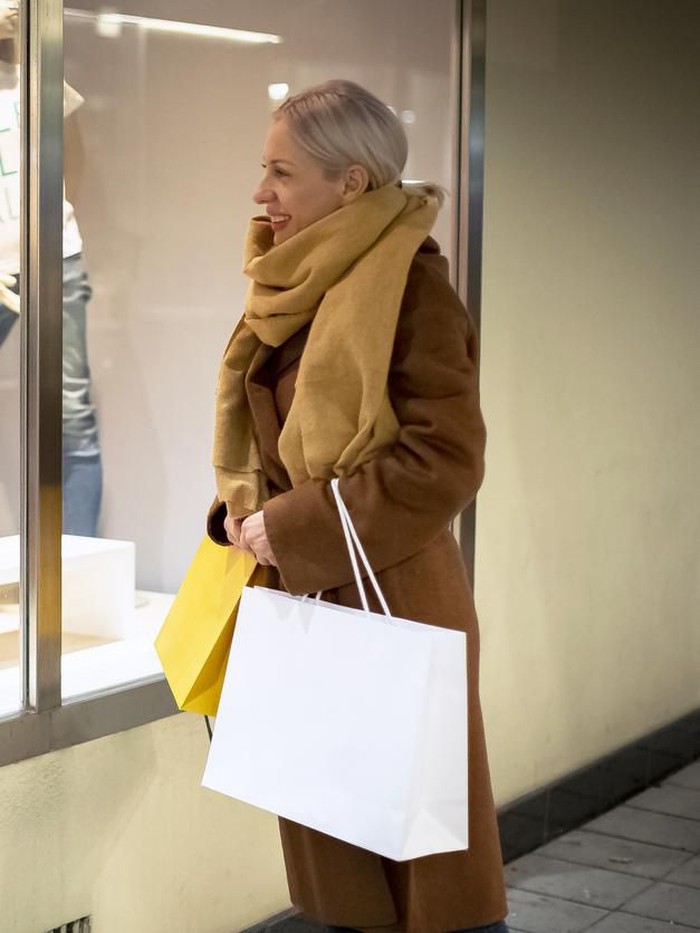 Happy woman shopping and looking at a window and carrying bags