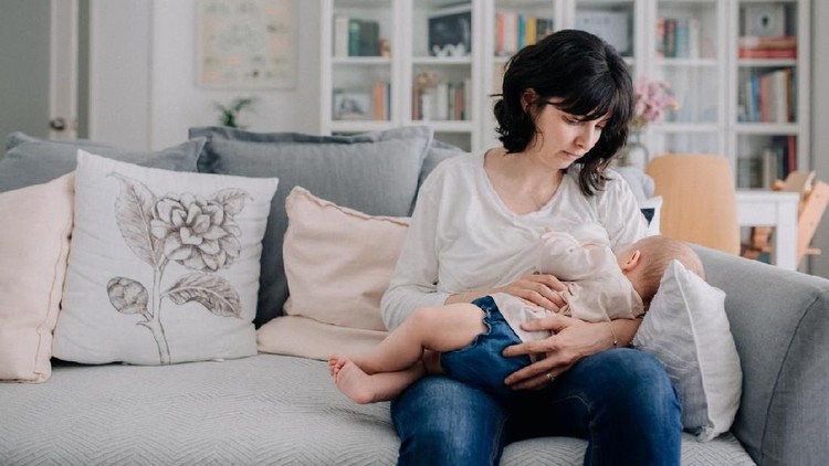 A woman breastfeeds her baby daughter