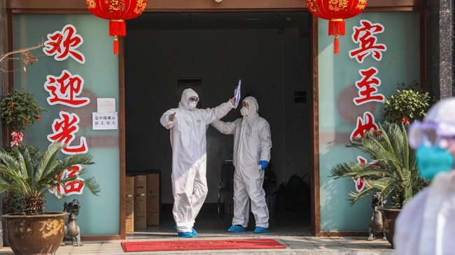 This photo taken on February 3, 2020 shows a medical staff member (L) being disinfected by a colleague before leaving a quarantine zone converted from a hotel in Wuhan, the epicentre of the new coronavirus outbreak, in China's central Hubei province. - The number of total infections in China's coronavirus outbreak has passed 20,400 nationwide with 3,235 new cases confirmed, the National Health Commission said on February 4. (Photo by STR / AFP) / China OUT