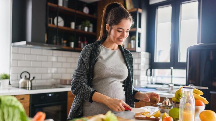 Young beautiful pregnant woman preparing healthy meal with fruites and vegetables