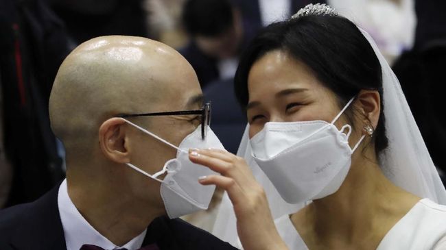 Pernikahan Massal di Korea Selatan Dihantui Virus Korona A couple wears masks in a mass wedding ceremony at the Cheong Shim Peace World Center in Gapyeong, South Korea, Friday, Feb. 7, 2020. South Korean and foreign couples exchanged or reaffirmed marriage vows in the Unification Church's mass wedding arranged by Hak Ja Han Moon, wife of the late Rev. Sun Myung Moon, the controversial founder of the church. (AP Photo/Ahn Young-joon)