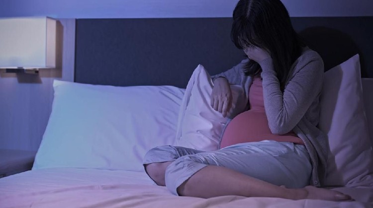 pregnant woman sit on the bed and feel depression at home