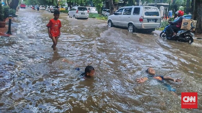 Area banjir di Bungur Raya Sahari dijadikan arena bermain oleh anak-anak kendati kendaraan masih melintas. 