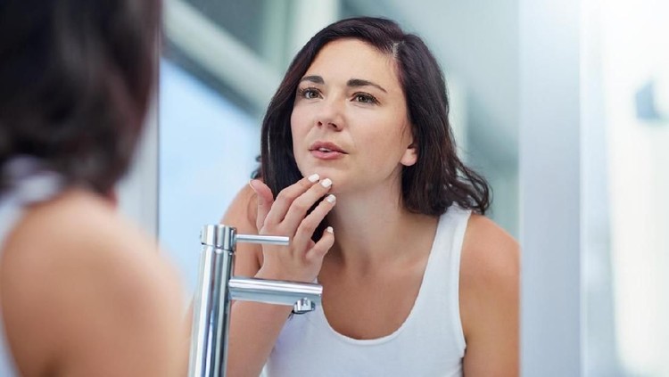 Shot of an attractive young woman covering her eye with a beauty product in her bathroom at home