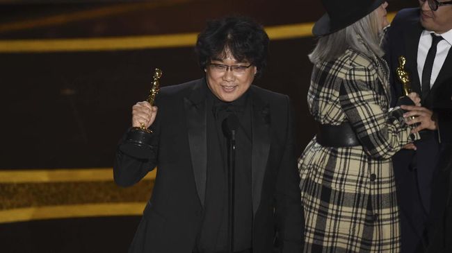 Senyum sutradara Bong Joon-ho mengembang memandangi piala perdana Oscar 2020 yang ia terima di malam penganugerahan.