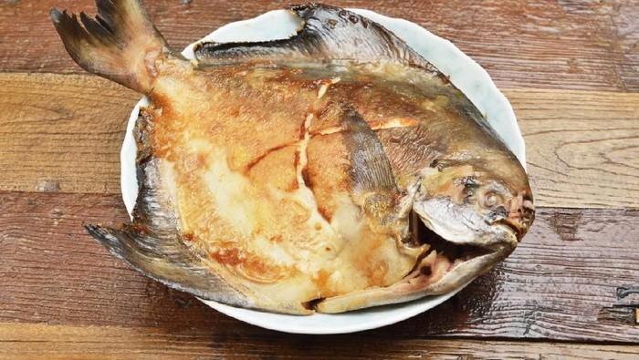 Fried white pomfret on wooden table