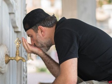 Istanbul, Turkey - April 07, 2012: Man performing ablution. Ablution is a ritual act, where the person washes himself/herself in order to get ready for the prayer. Image taken during midday at the fountains next to Sultanahmet Mosque in Istanbul.