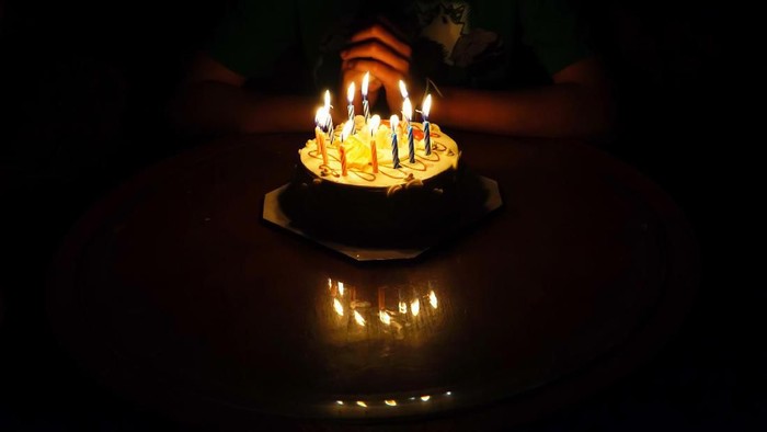 The boy is requesting blessings on his birthday by having a cake.