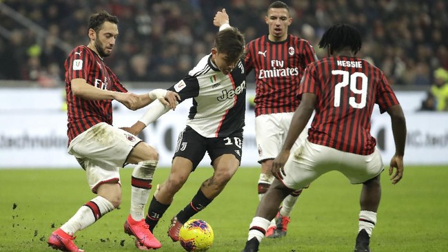Juventus' Paulo Dybala, second left, fights for the ball with AC Milan's Hakan Calhanoglu, left, AC Milan's Ismael Bennacer, right, and AC Milan's Ismael Bennacer during an Italian Cup soccer match between AC Milan and Juventus at the San Siro stadium, in Milan, Italy, Thursday, Feb. 13, 2020. (AP Photo/Luca Bruno)
