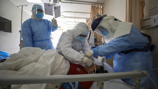 In this Sunday, Feb. 16, 2020, photo, medical workers provide treatment to a new coronavirus patient at a hospital in Wuhan in central China's Hubei province. Chinese authorities on Monday reported a slight upturn in new virus cases and hundred more deaths for a total of thousands since the outbreak began two months ago. (Chinatopix via AP)