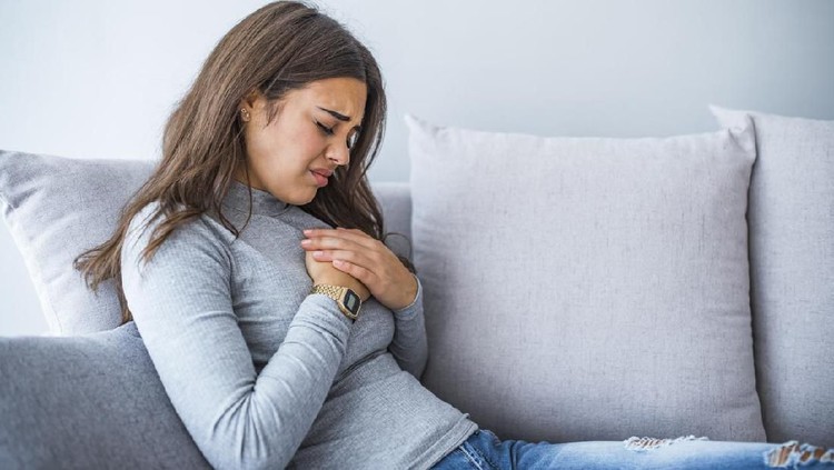 Woman holding hand to spot of pain area, chest pain, Health care concept. Sick woman with indigestion problem, acid reflux or gerd symptoms; woman health care, body care, sickness, pain, acid reflux concept