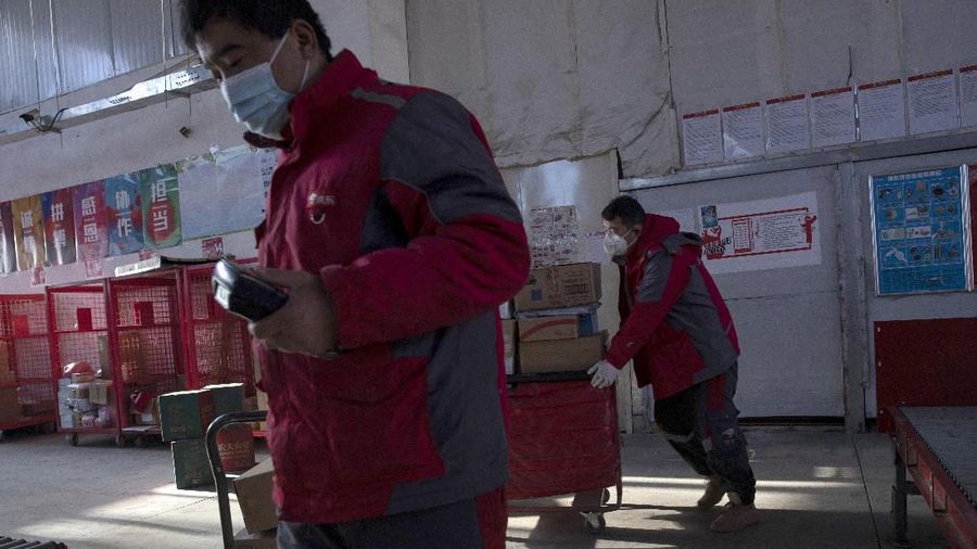 In this Tuesday, Feb. 18, 2020, photo, a resident looks for her parcel near a temporary No Contact parcel collection point for Chinese e-commerce giant JD.com outside an apartment complex in Beijing, China. JD and rivals including Pinduoduo, Miss Fresh and Alibaba Group's Hema are scrambling to fill a boom in orders while protecting their employees. E-commerce is one of the few industries to thrive after anti-virus controls starting in late January closed factories, restaurants, cinemas, offices and shops nationwide and extinguished auto and real estate sales. (AP Photo/Ng Han Guan)