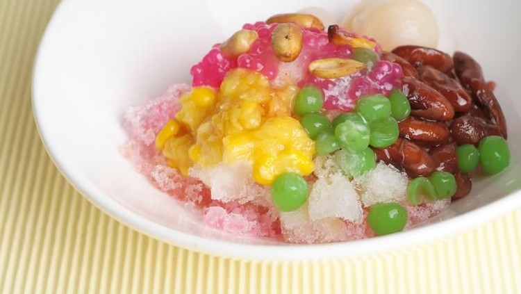 Es Teler, an Indonesian iced dessert of tropical fruit cocktail. Coconut, jackfruit, and avocado with sweet coconut milk soup and crushed ice. Served in ceramic bowl and saucer.