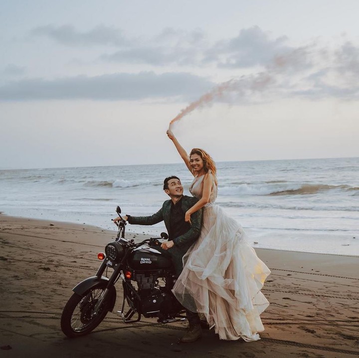 <p>Mezty tampak cantik mengenakan gaun putih, berpose dengan Gerald yang naik motor di pinggir pantai saat foto pre-wedding. (Foto: Instagram @meztymez)</p>