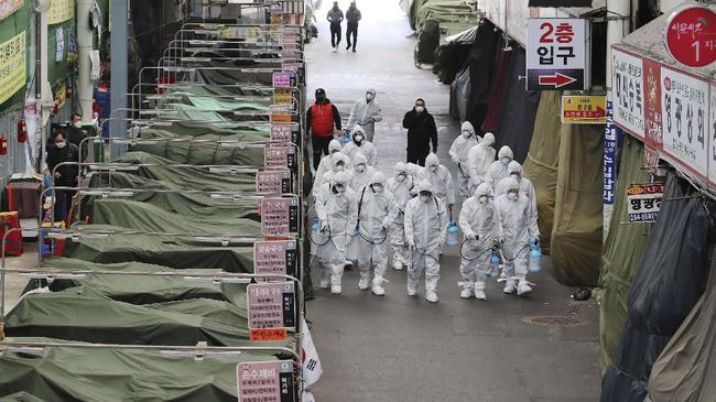 Workers wearing protective gear spray disinfectant as a precaution against the COVID-19 coronavirus in a local market in Daegu, South Korea, Sunday, Feb. 23, 2020. South Korea's president has put the country on its highest alert for infectious diseases and says officials should take 