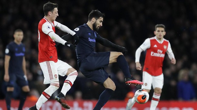 Everton's Andre Gomes, right, is challenged by Arsenal's Mesut Ozil during the English Premier League soccer match between Arsenal and Everton at Emirates stadium in London, Sunday, Feb. 23, 2020. (AP Photo/Kirsty Wigglesworth)