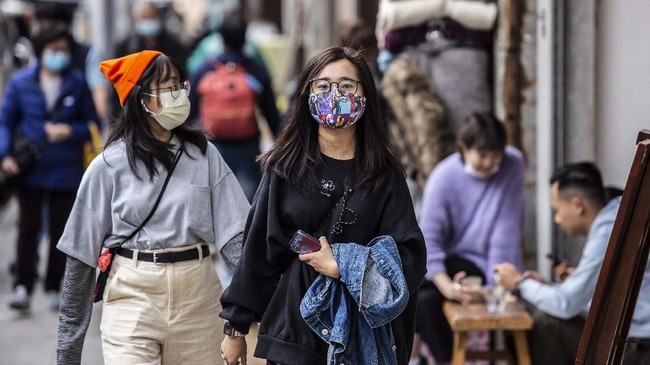 This picture taken on February 20, 2020 shows a woman (centre R) wearing a mask made out of patterned material in Hong Kong. - Faced with shortages in the midst of a virus outbreak, Hong Kongers have started making their own face masks, from professional factories to seamstresses churning out coverings on sewing machines. (Photo by ISAAC LAWRENCE / AFP)