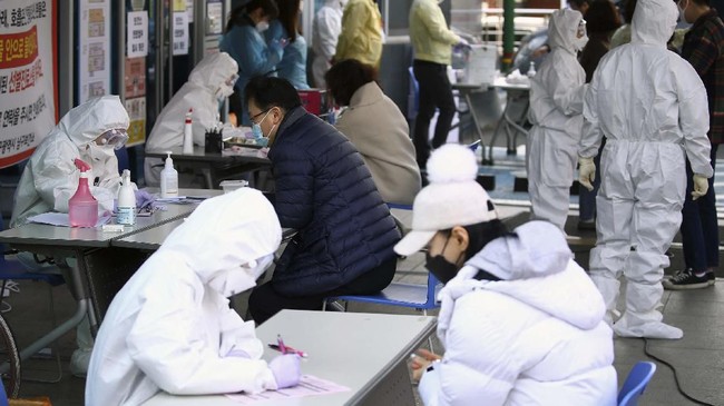 People suspected of being infected with the new coronavirus talk with medial center workers to receive tests in Daegu, South Korea, Friday, Feb. 21, 2020. South Korea reported 100 new virus cases Friday, bringing the country's total to 204, many of them clustered around a southeastern city, and raising fears that the outbreak is getting out of control. (Kim Hyun-tae/Yonhap via AP)