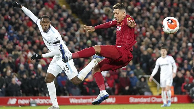 Liverpool's Roberto Firmino attempts to kick the ball to the goal as West Ham's Issa Diop, left, watches the English Premier League soccer match between Liverpool and West Ham at Anfield Stadium in Liverpool, England, Monday, Feb. 24, 2020. (AP Photo/Jon Super)