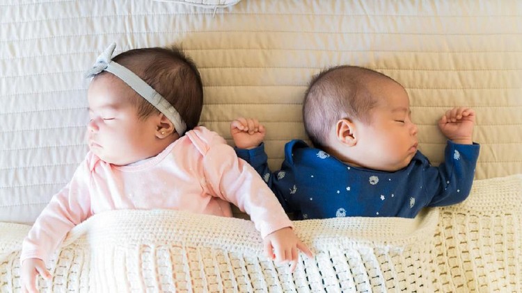 nama bayi High angle view of cute newborn Latin twins sleeping together on bed