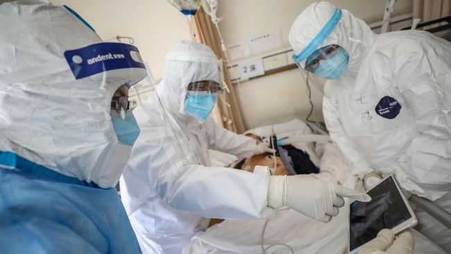This photo taken on February 16, 2020 shows a doctor looking at an image as he checks a patient who is infected by the COVID-19 coronavirus at the Wuhan Red Cross Hospital in Wuhan in China's central Hubei province. - The death toll from the COVID-19 coronavirus epidemic jumped to 1,770 in China after 105 more people died, the National Health Commission said February 17. (Photo by STR / AFP) / China OUT