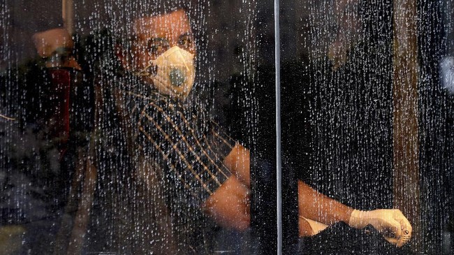 A commuter looks through a water-stained window wearing a mask and gloves to help guard against the Coronavirus, on a public bus in downtown Tehran, Iran, Sunday, Feb. 23, 2020. Iran's health ministry raised Sunday the death toll from the new virus to 8 people in the country, amid concerns that clusters there, as well as in Italy and South Korea, could signal a serious new stage in its global spread. (AP Photo/Ebrahim Noroozi)