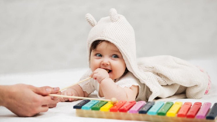 Happy little kid, baby girl in 1 year plays a musical instrument xylophone in game center, of the children's room for birthday or home.