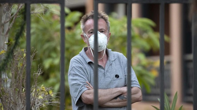 A man wearing a face mask looks out from the H10 Costa Adeje Palace hotel in La Caleta, in the Canary Island of Tenerife, Spain, Friday Feb. 28, 2020. Some guests have started to leave the locked down hotel after undergoing screening for the new virus that is infecting hundreds worldwide. (AP Photo/Joan Mateu)