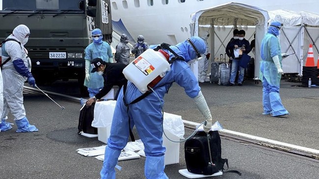 Petugas kesehatan menyemprotkan cairan disinfektan kepada WNI ABK Diamond Princess dan barang bawaan saat turun dari kapal di Yokohama, Jepang, Minggu (2/3/3030). Pemerintah mengevakuasi 69 WNI ABK Diamond Princess yang dinyatakan negatif COVID-19 untuk dipulangkan ke tanah air dan diosevasi di pulau Sebaru Kecil, Kepulauan Seribu. ANTARA FOTO/HO/KBRI Tokyo/wpa/hp.;