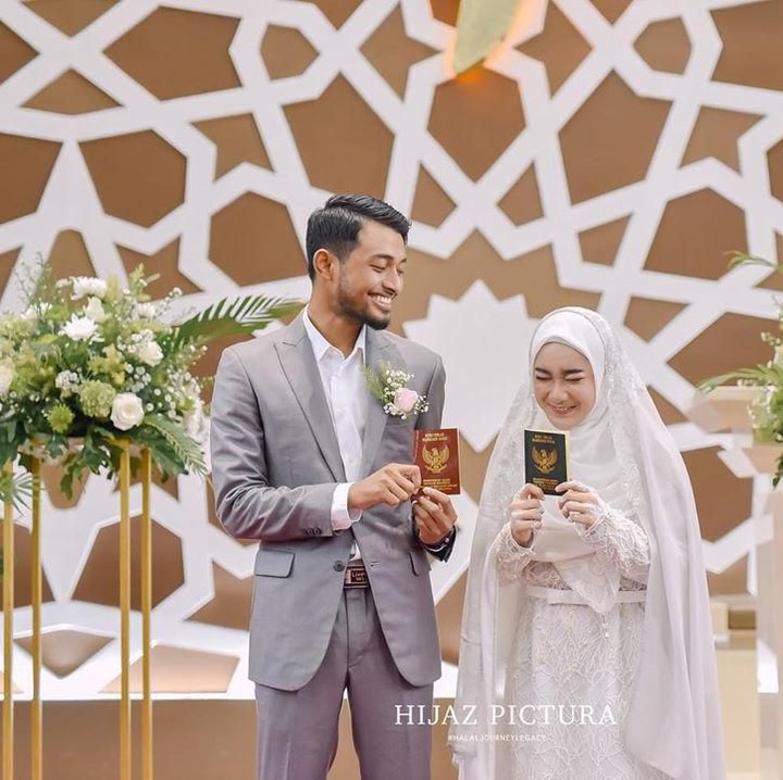 <p>Tak kuasa menahan rasa bahagia, Hawaariyyun dan Dena tersenyum sambil menunjukkan buku nikah. (Foto: Instagram @benzoitubejo)</p>