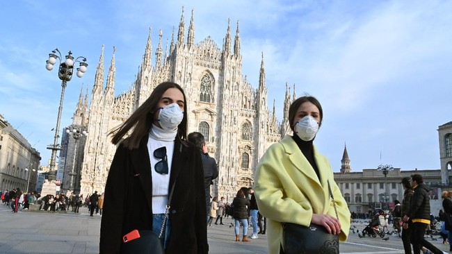 Women wearing a respiratory mask walk across Piazza del Duomo in central Milan on February 23, 2020. - Tens of thousands of Italians prepared for a weeks-long quarantine in the country's north on February 23 as nerves began to fray among the locals faced with new lockdown measures. (Photo by ANDREAS SOLARO / AFP)