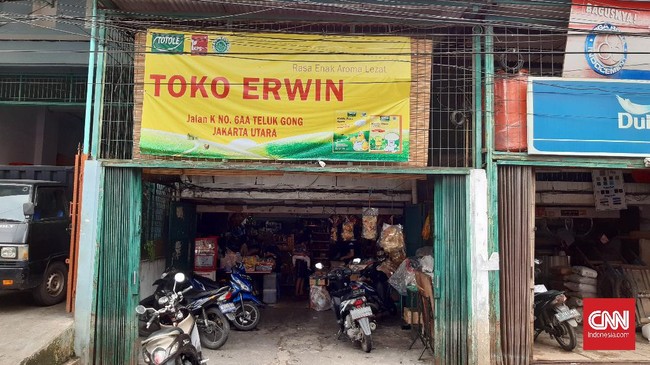 Erwin, pemilik toko kelontong di Teluk Gong menolak pembeli yang akan memborong kebutuhan pokok dengan harga tinggi. Ia lebih memilih melayani warga sekitar.