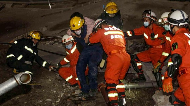 Seorang wanita diselamatkan dari reruntuhan hotel yang digunakan sebagai lokasi karantina virus Corona di Quanzhou, China, Sabtu (7/3). Hotel tersebut ambruk Sabtu (7/3). (Photo by STR / AFP) / China OUT.