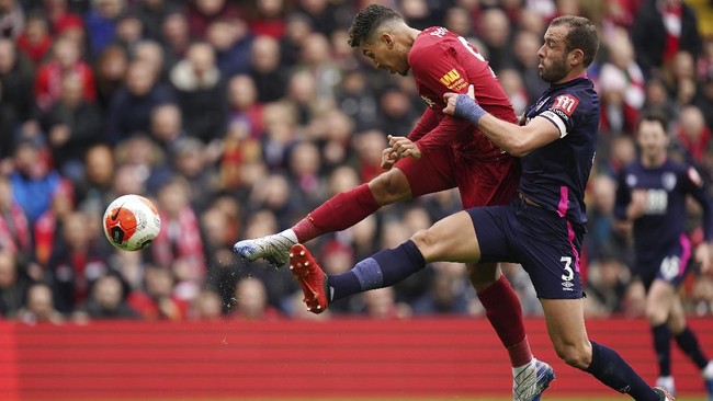 Liverpool's Roberto Firmino, left, challenges for the ball with Bournemouth's Steve Cook during the English Premier League soccer match between Liverpool and Bournemouth at Anfield stadium in Liverpool, England, Saturday, March 7, 2020. (AP Photo/Jon Super)