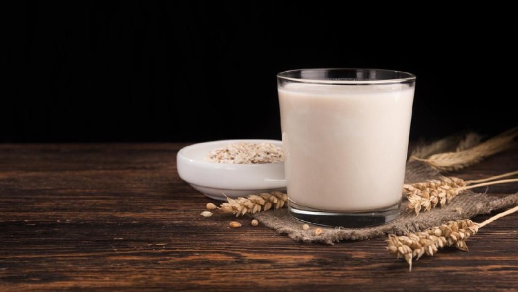 A glass of oat milk and cereal oatmeal on a wooden table. Vegetarian diet concept.