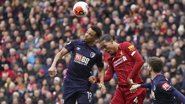 Bournemouth's Junior Stanislas, left, jumps for the ball with Liverpool's Virgil van Dijk, center, during the English Premier League soccer match between Liverpool and Bournemouth at Anfield stadium in Liverpool, England, Saturday, March 7, 2020. (AP Photo/Jon Super)