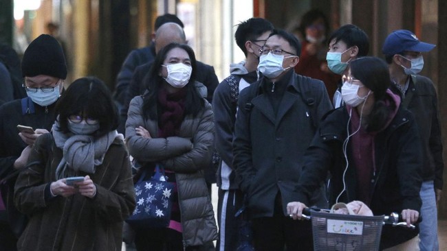 People wearing face masks as a precaution against the new coronavirus stand on a street in Taipei, Taiwan, Thursday, March 5, 2020. (AP Photo/Chiang Ying-ying)
