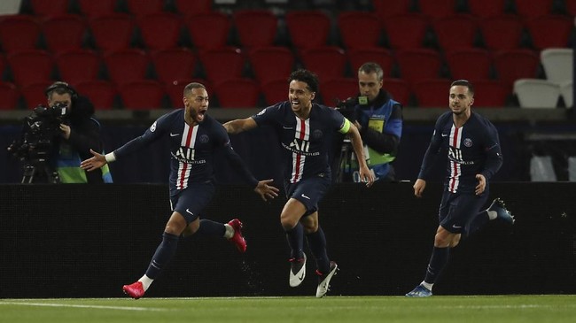 Paris Saint Germain's Neymar celebrates with teammate Marquinhos, center, after scoring his side's first goal during the Champions League round of 16 second leg soccer match between PSG and Borussia Dortmund, Wednesday March 11, 2020 in Paris. The match is being played in an empty stadium because of the coronavirus outbreak. (UEFA via AP)