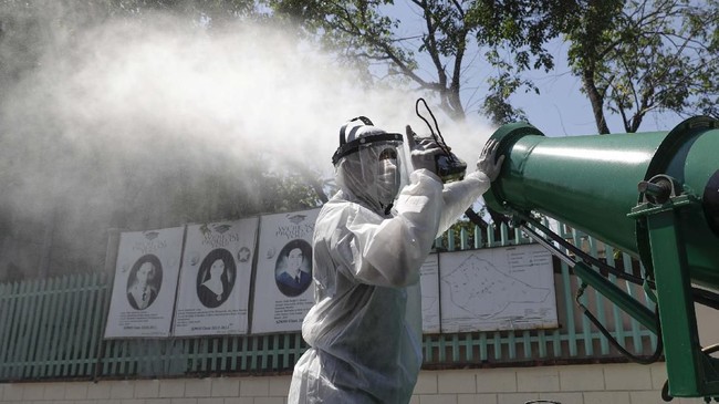 A worker in protective suit controls a big disinfectant spray as they sanitize a school which has suspended classes as a precautionary measure against a new coronavirus in San Juan city, east of Manila, Philippines on Monday, March 9, 2020. Philippine President Rodrigo Duterte has declared a state of public health emergency throughout the country after health officials confirmed over the weekend the first local transmission of the new coronavirus. (AP Photo/Aaron Favila)